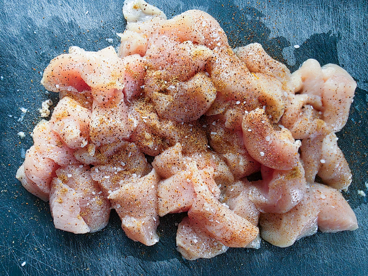 Chicken seasoned with spices on a black board.