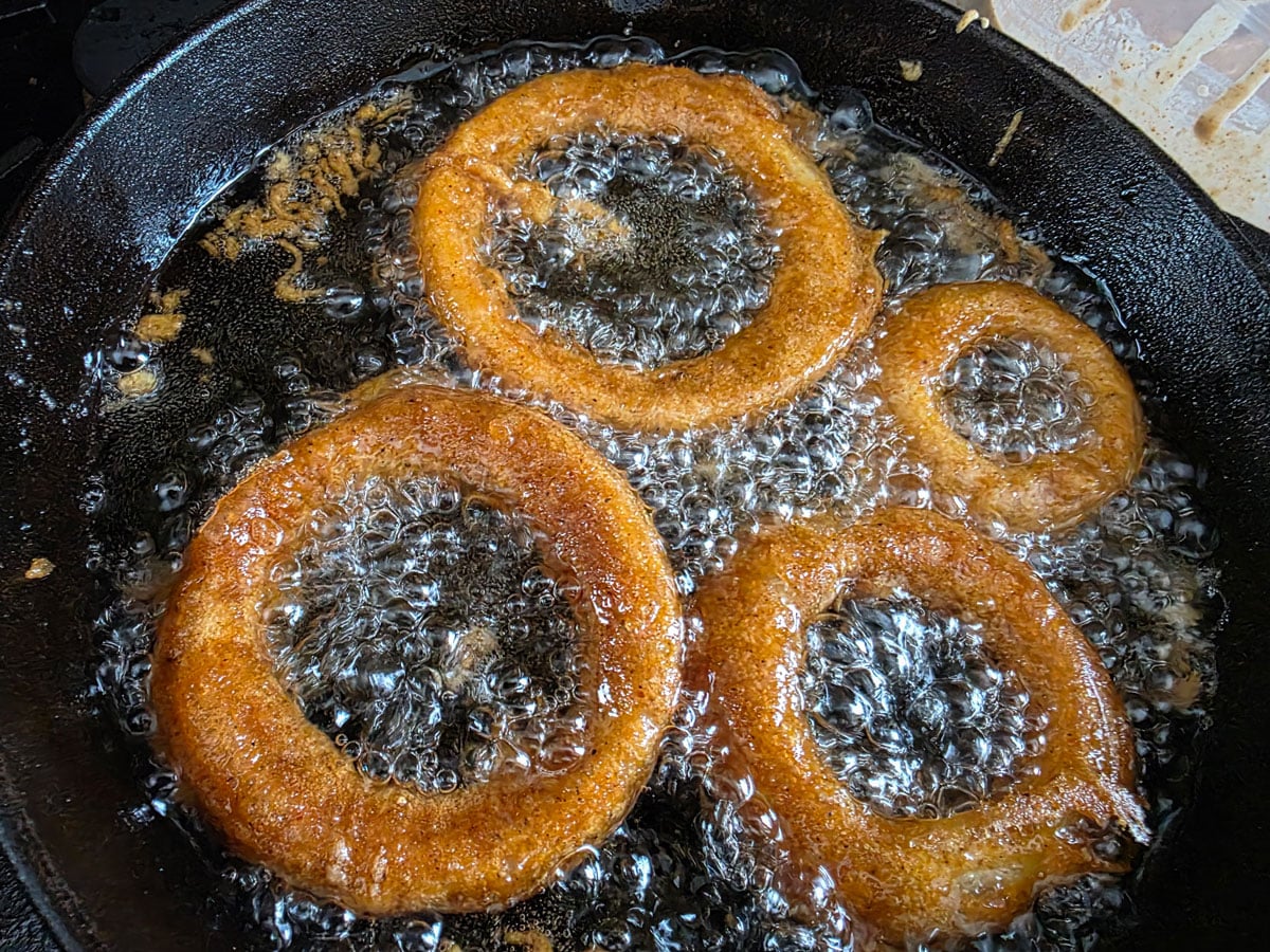 four large onion rings cooking in oil.