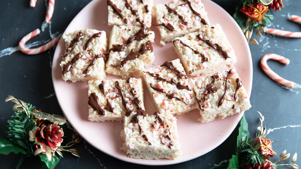 Peppermint rice krispies treats drizzled with chocolate on a pink plate.