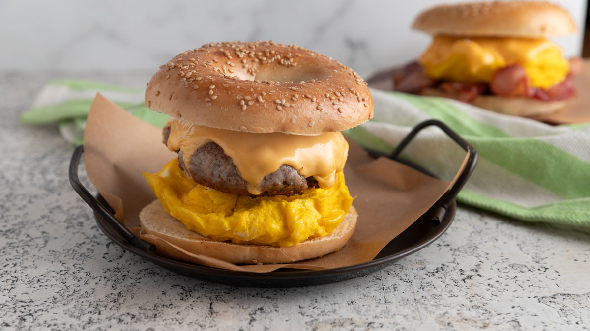 Sausage and eggs breakfast sandwich on a metal tray.
