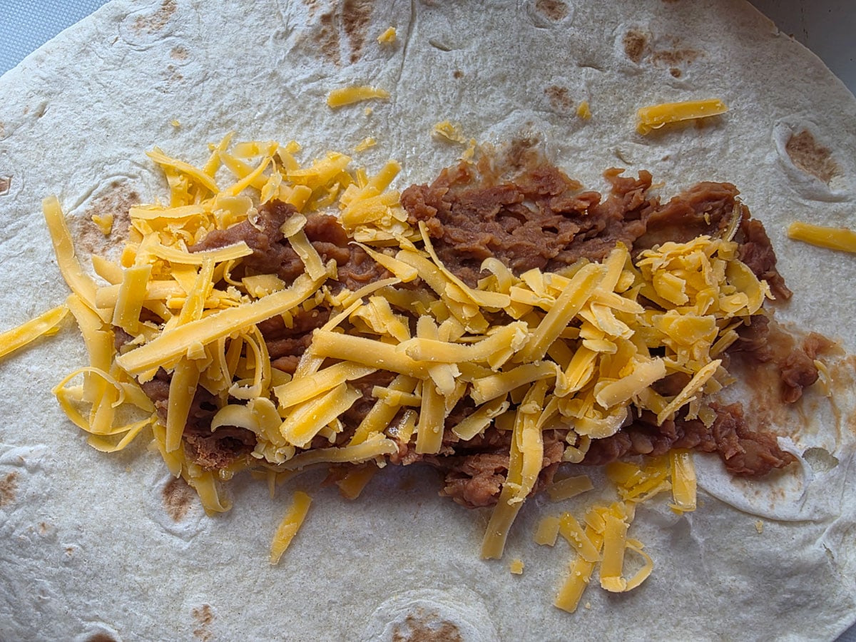 Beans and cheese spread on a tortilla.