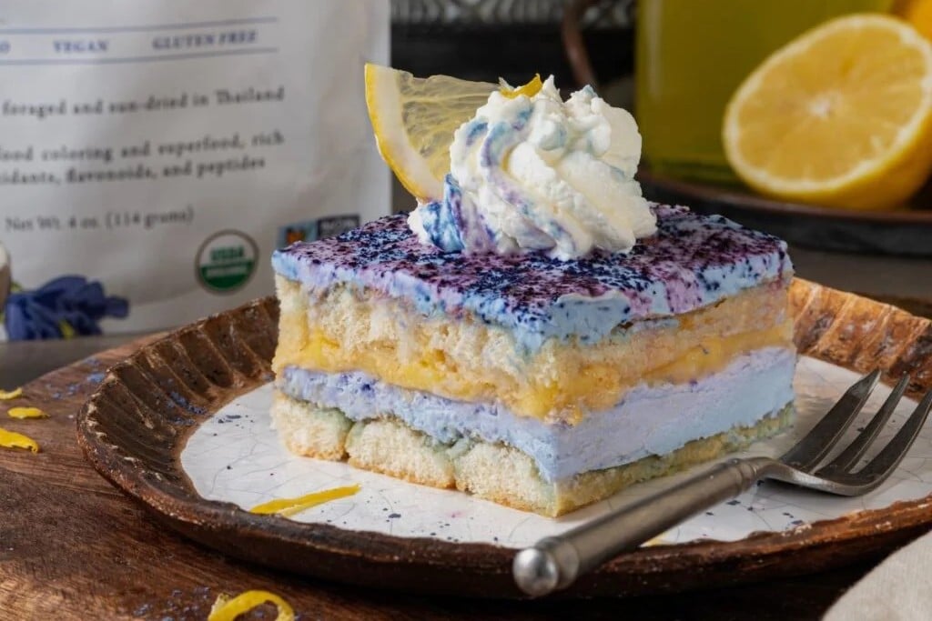 A slice of Butterfly Pea Lemon Tiramisu with a fork on the side.