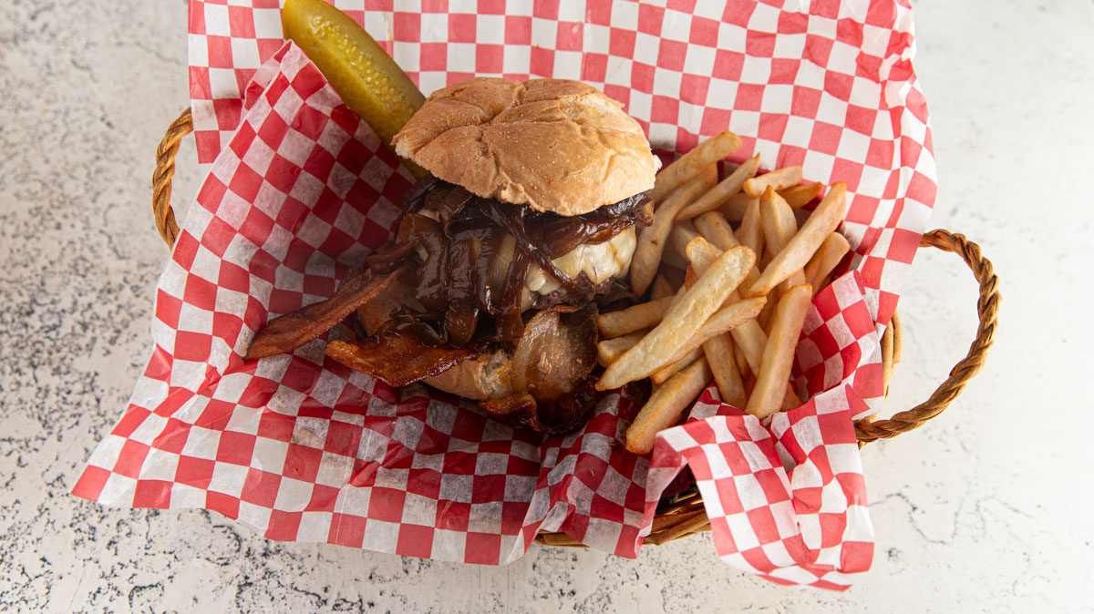 Caramelized onion burger in a basket with red and white checked paper.