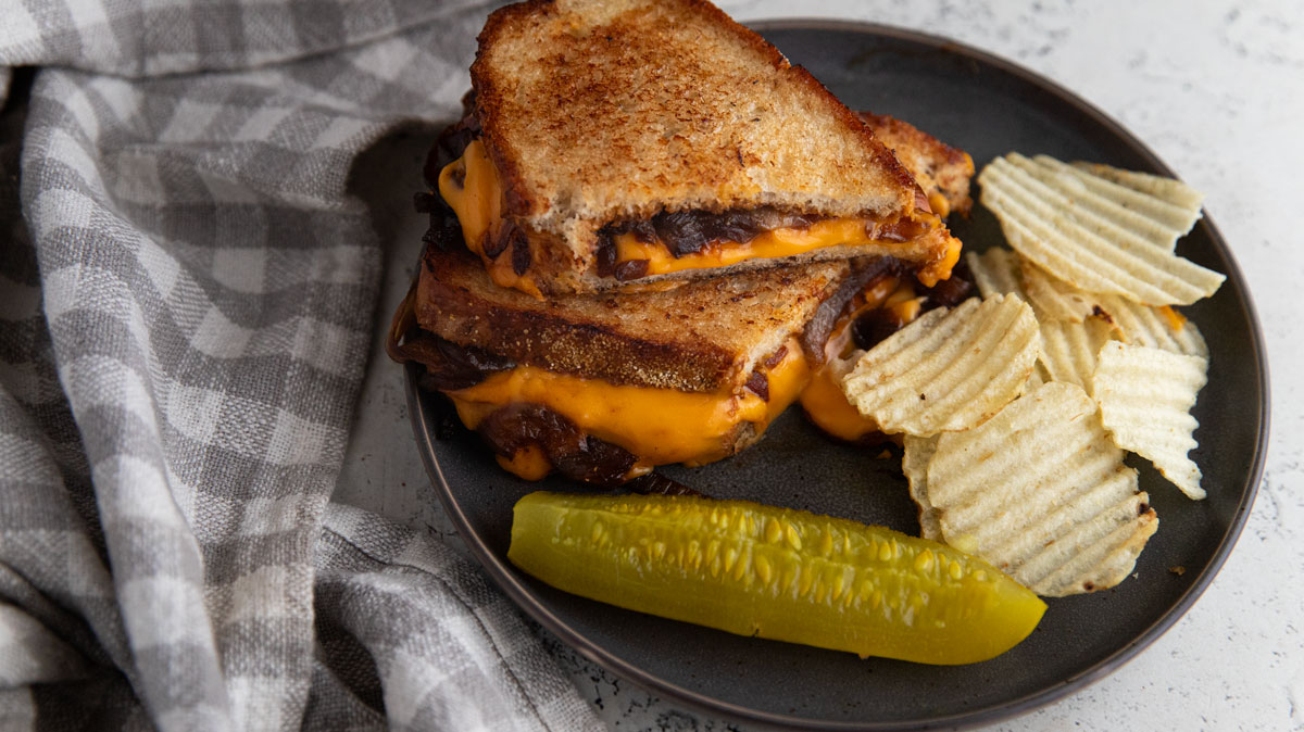 Caramelized onion grilled cheese on a plate with sides.