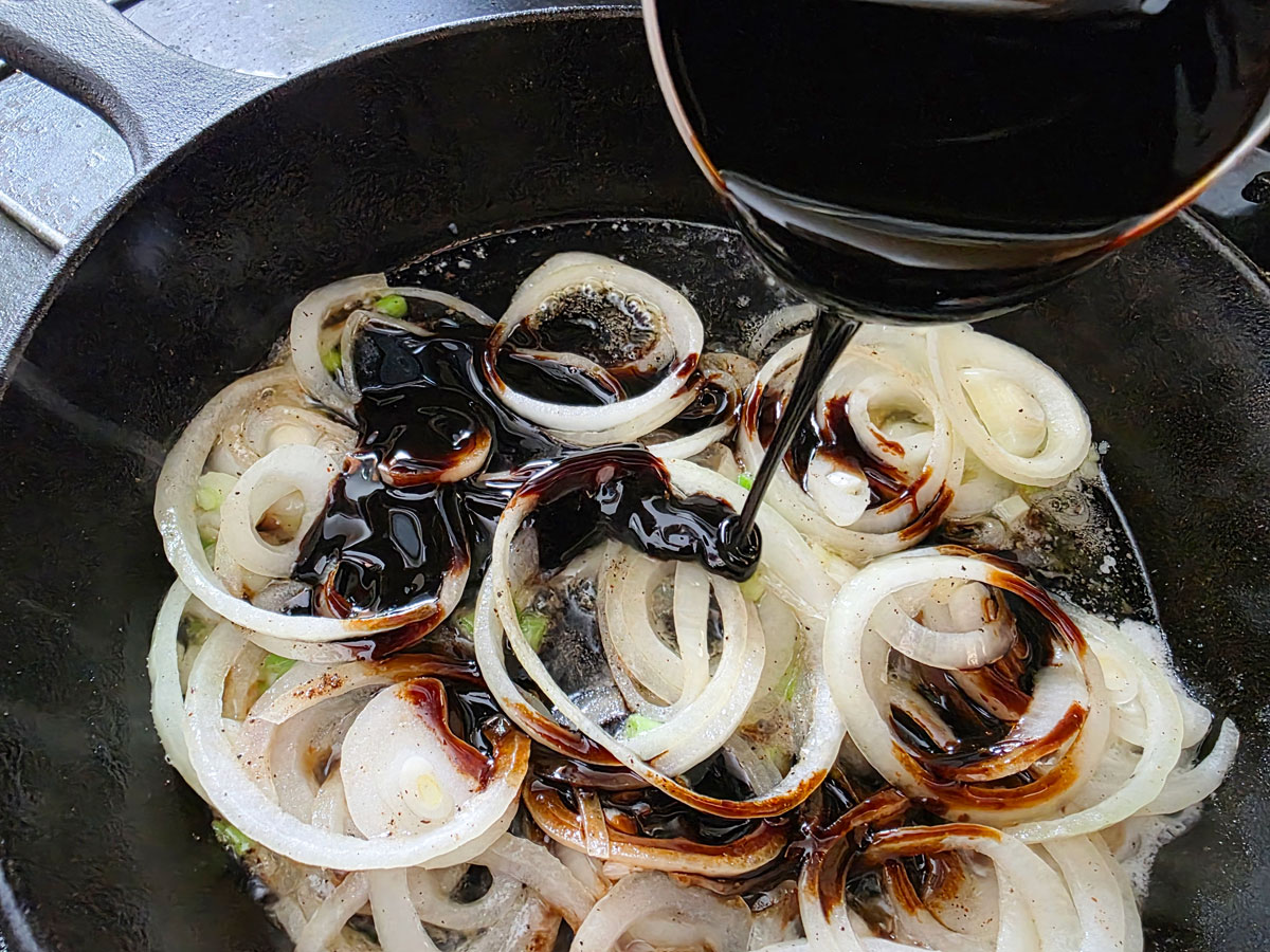 Pouring molasses into softened onion in the skillet.