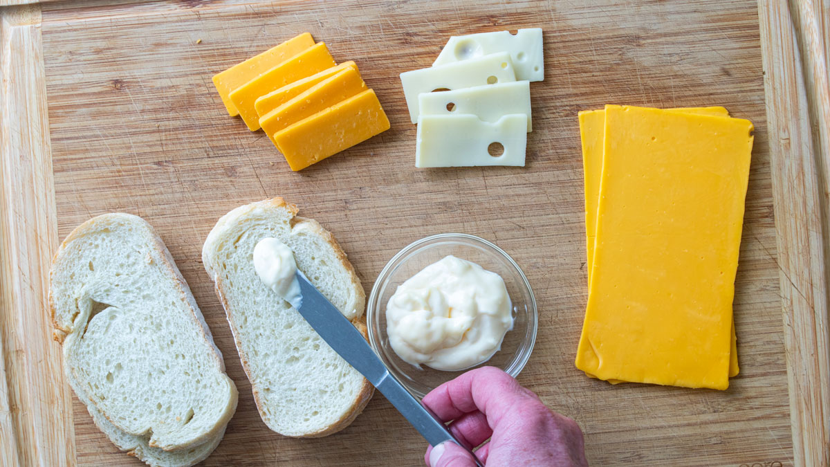 Spreading mayonnaise on a slice of bread.