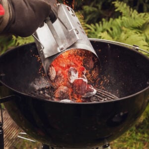Pouring charcoal briquets from a chiney starter.