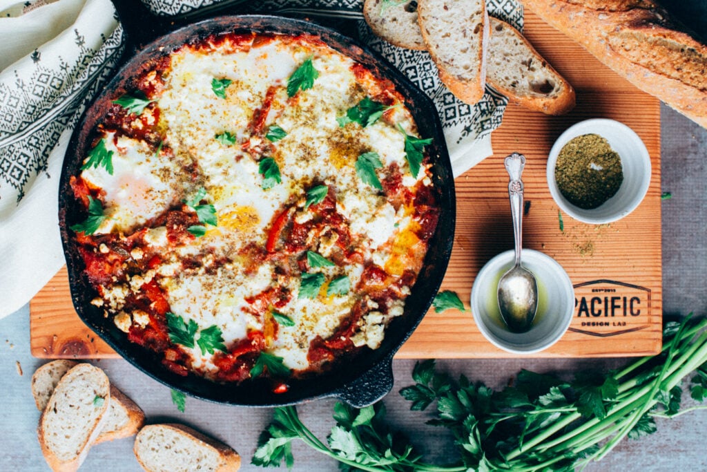 A skillet of Shakshuka (Baked eggs in Tomato Sauce) with Broiled Feta