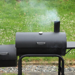 Offset smoker with grass in the background.