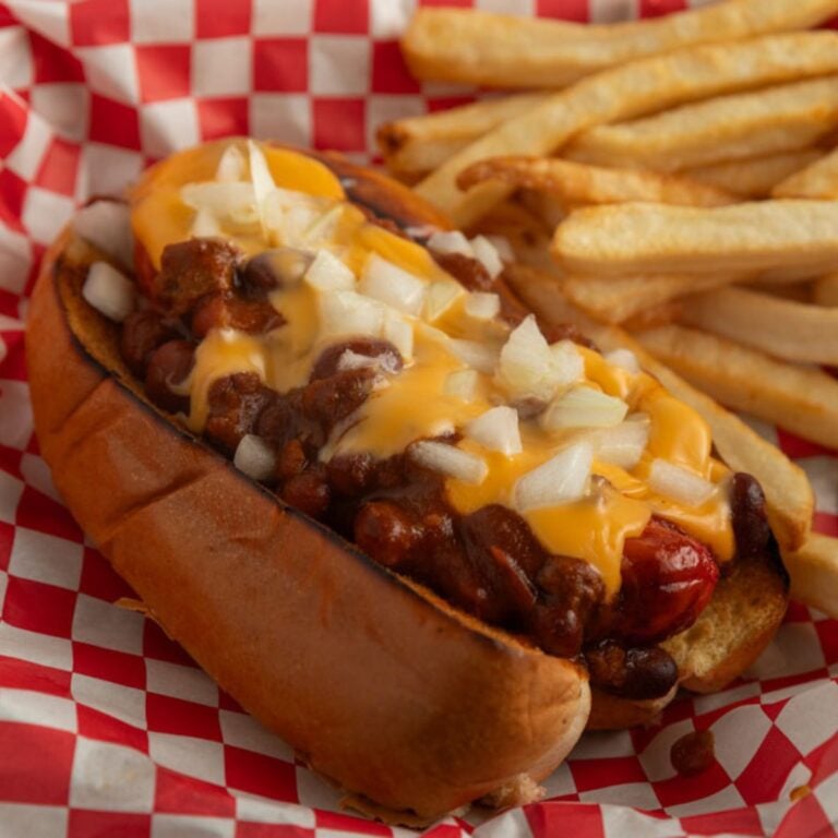 Close up of chili dog topped with cheese and onions.