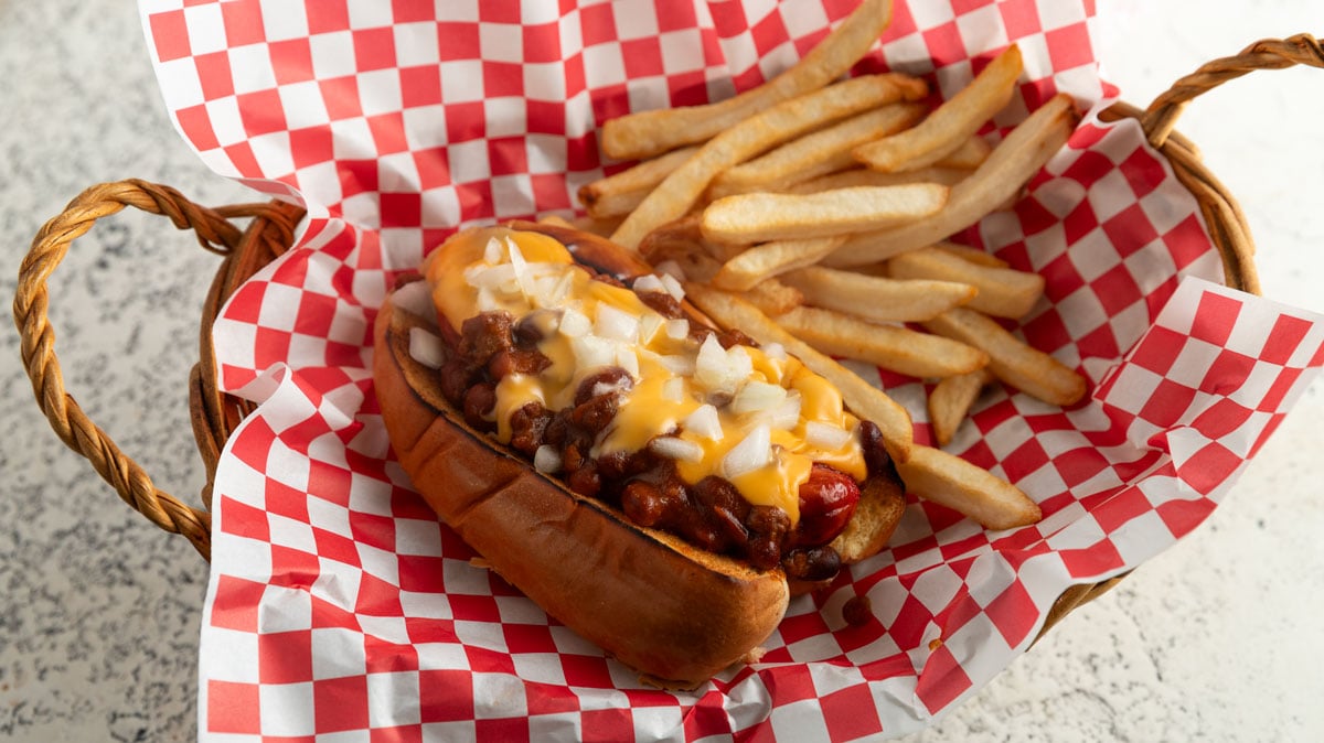 Chili dog in a basket with red checked paper.