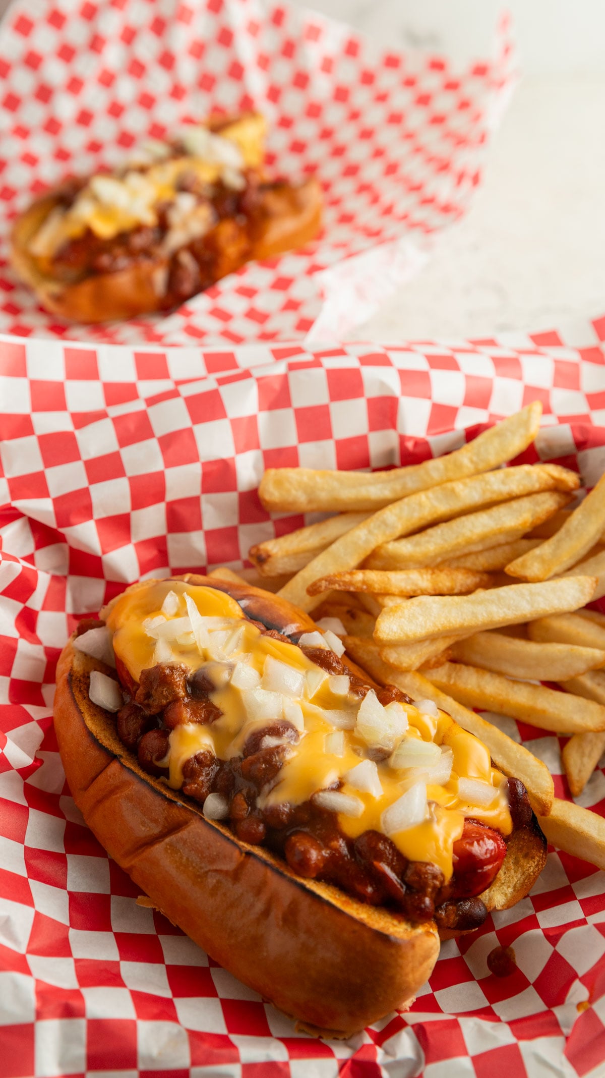 Chili cheese dogs in a basket with red checked paper.