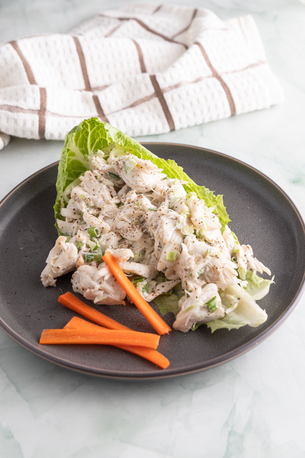 Crab salad on a gray plate in a lettuce wrap.