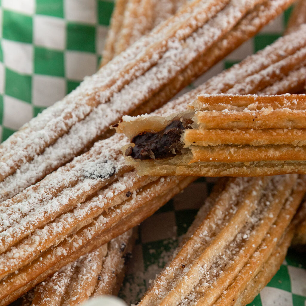 Bite taken out of an air fried churro with chocolate filling.