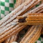 Bite taken out of an air fried churro with chocolate filling.