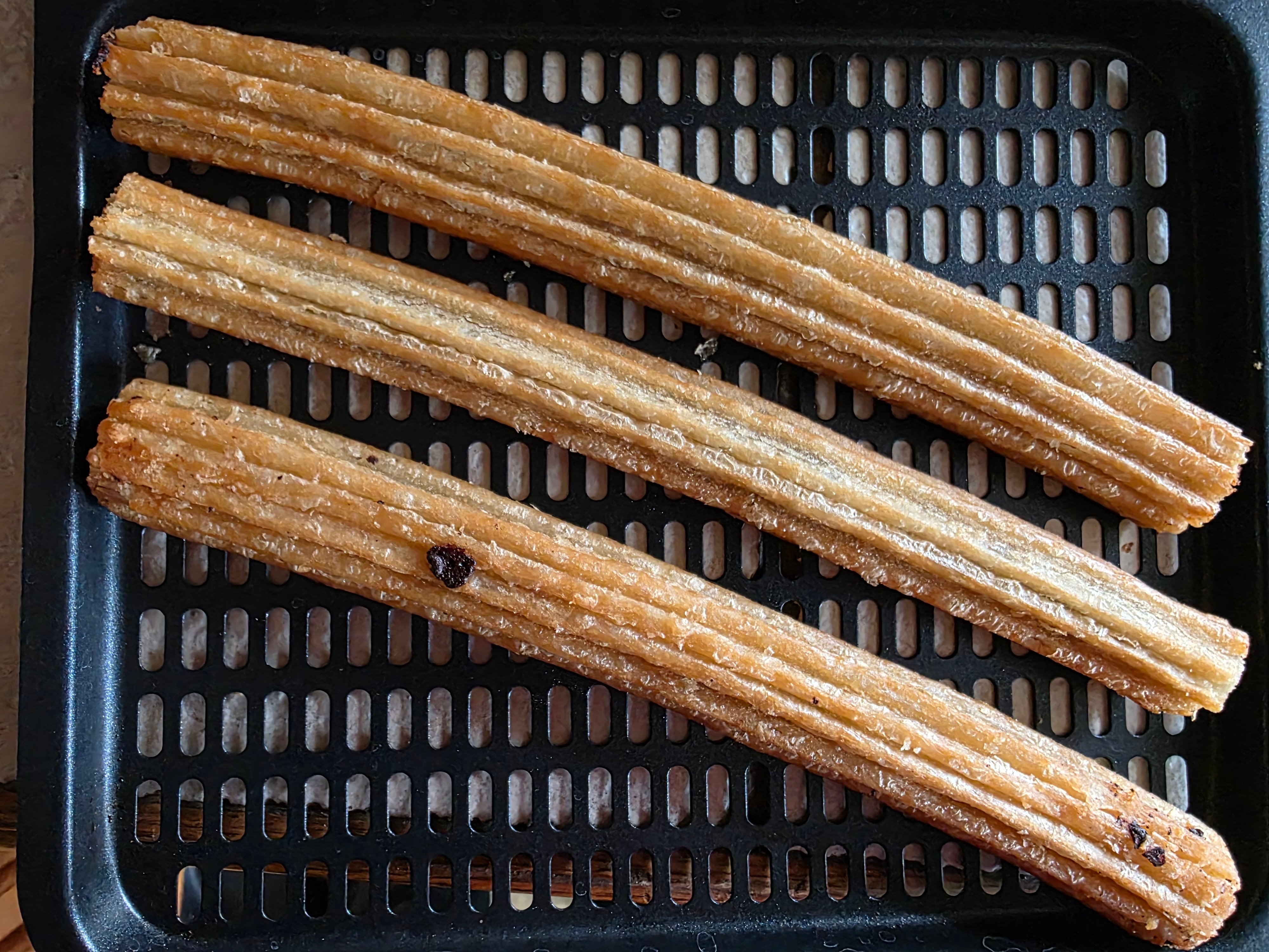 Frozen churros placed in the air fryer basket.