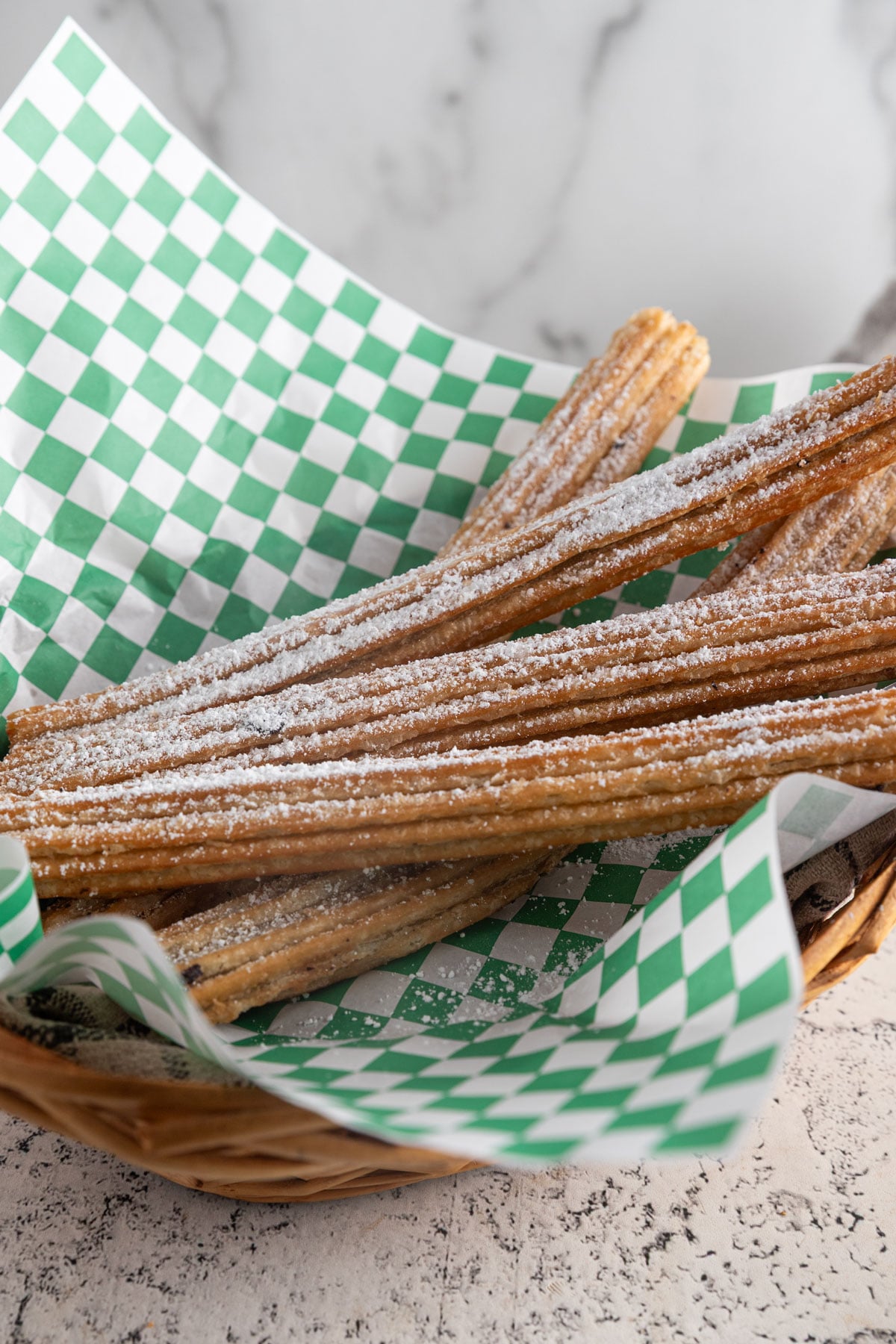 Churros in a basket with green and white checked paper.
