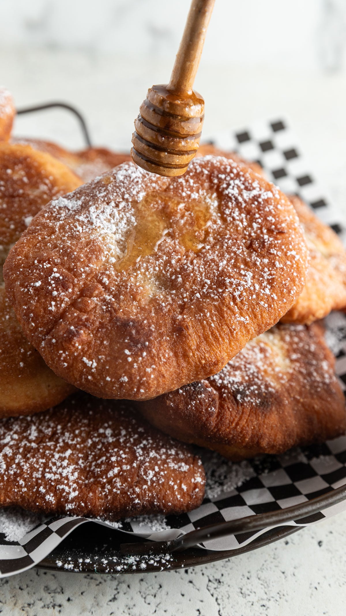 Honey dipper dripping honey onto fried dough.