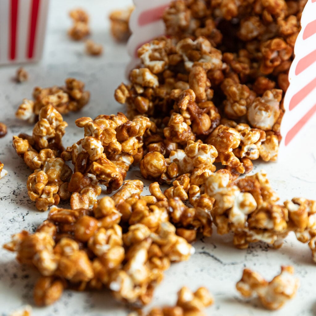 Clusters of caramel corn spilling from a popcorn box.