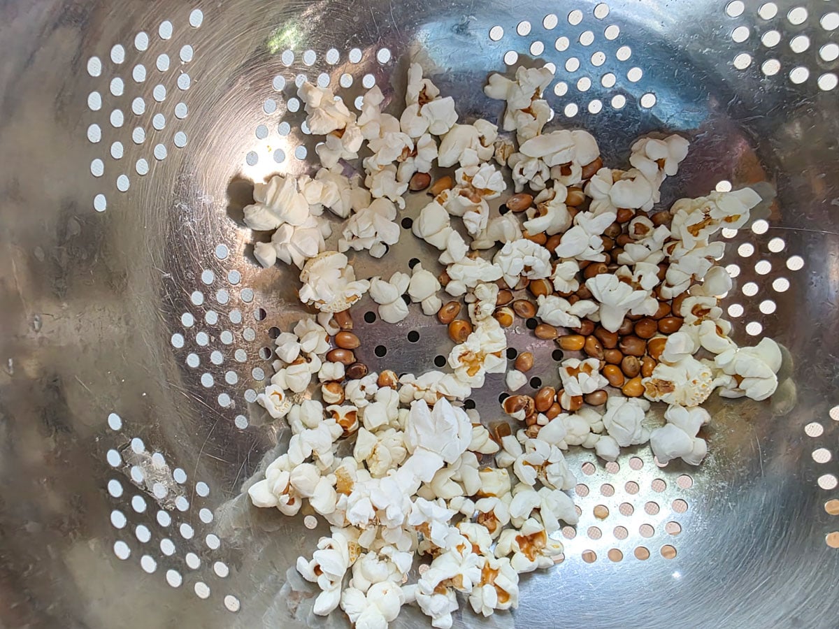 Unpopped corn kernels in a colander.
