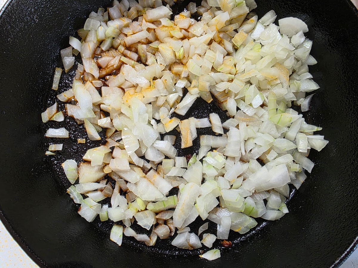 Onions sautëing in a cast iron skillet.