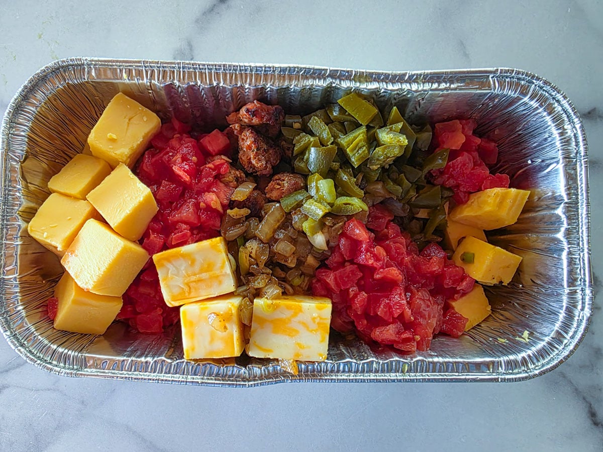 All queso ingredients in an aluminum pan.