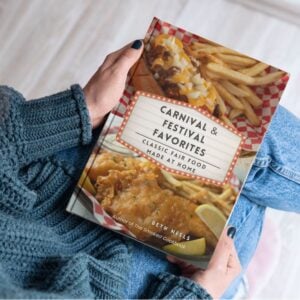Woman in a blue sweater and jeans holding Carnival & Festival Favorites.
