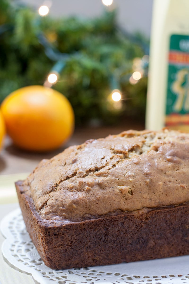 Whole loaf of egnog bread with an orange in the background.