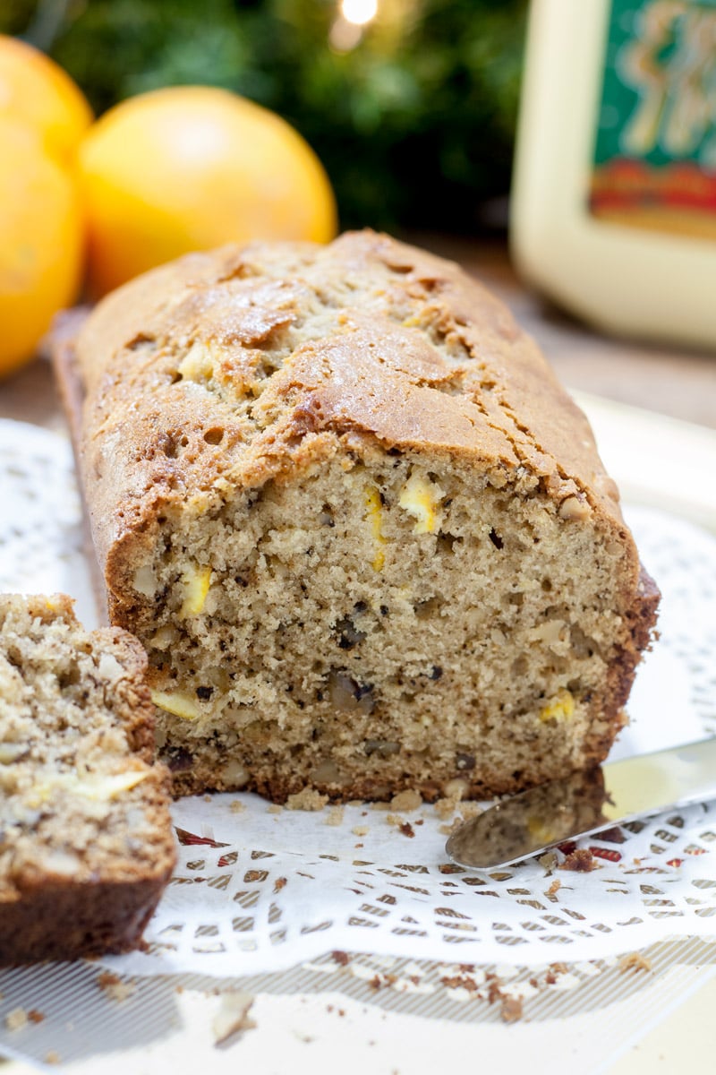 Slice of eggnog quick bread with oranges in the background.