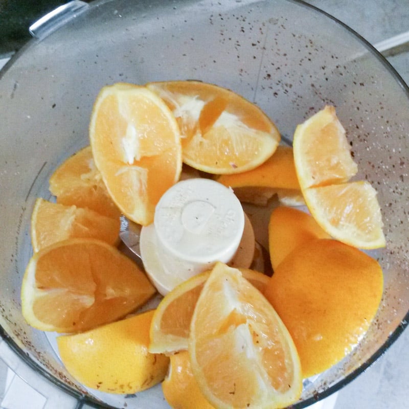Quartered oranges in a food processor bowl.