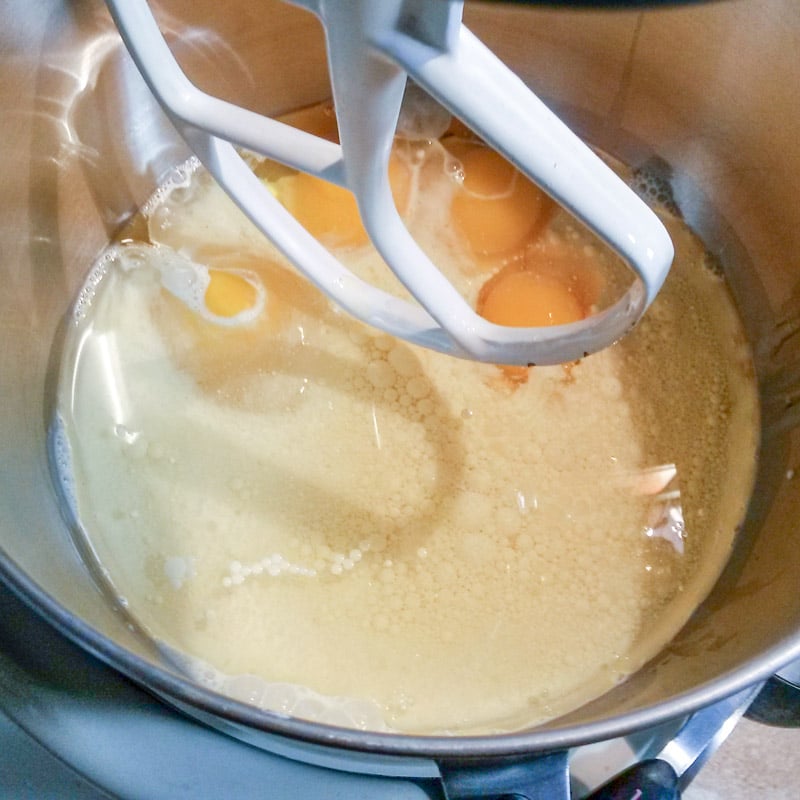 Eggs added to the oil and eggnog in a mixing bowl.