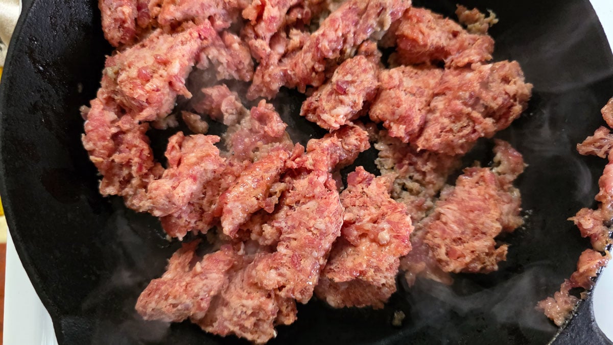 Browning sausage in a cast iron skillet.